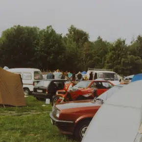 Autos und Zelte auf einer provisorischen Campingfläche.