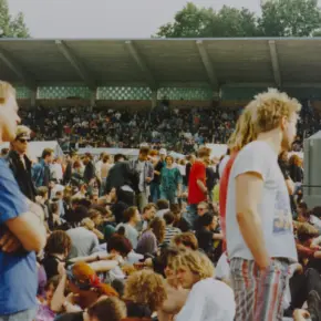 Festivalbesucher sitzen und stehen im Innenraum, im Hintergrund sind die Stadionränge zu sehen.